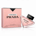 Productfoto van Prada Paradoxe Eau de Parfum (90 ml). De kenmerkende driehoekige glazen flacon met lichtroze inhoud en zwarte dop leunt rechts tegen de bijpassende roze, getextureerde doos.